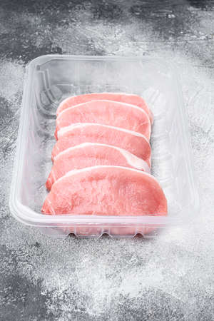 Raw pork steak meat set, in plastic pack container, on gray stone table backgroundの写真素材