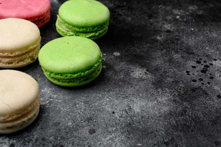 Sweet colorful macarons set, on black dark stone table background, with copy space for textの写真素材