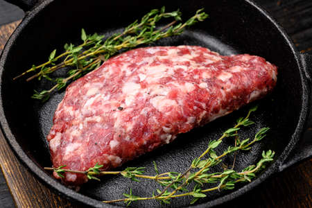 Fresh raw minced homemade farmers grill beef burgers set, in cast iron frying pan, on black wooden table backgroundの写真素材