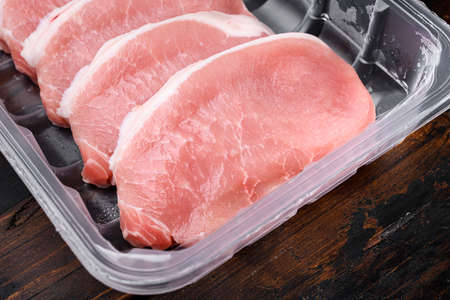 Pork chop sliced fresh meat set, in plastic pack container, on old dark wooden table backgroundの写真素材