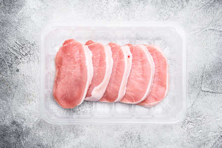 Fresh pork set, in plastic pack container, on gray stone table background, top view flat layの写真素材