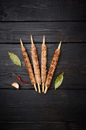 Kofta or lula beef and lamb meat kebabs skewers set, on black wooden table background, top view flat lay, with copy space for textの写真素材
