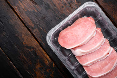 Sliced raw pork meat set, in plastic pack container, on old dark wooden table background, top view flat lay, with copy space for textの写真素材