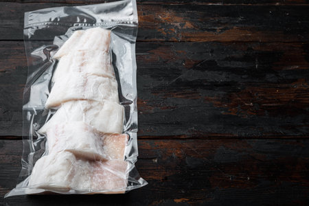 Haddock fish skinless in vacuum package, on old wooden table, top view with copy space for text