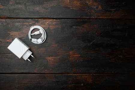 Usb charger pack for smartphone set on old dark wooden table background, top view flat lay, with copy space for textの写真素材