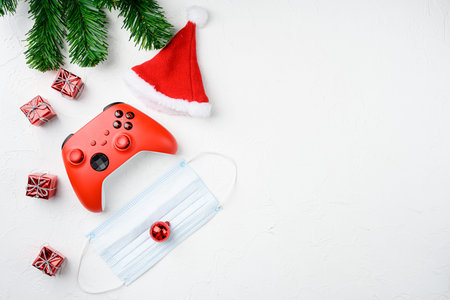 Joystick gaming controller with Christmas decoration set with mask, on white stone table background,...