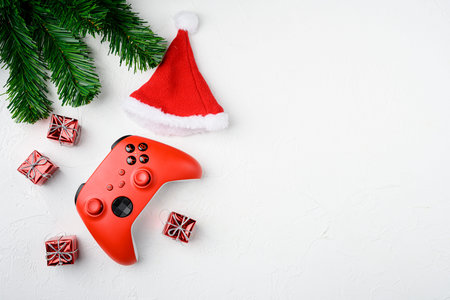 Red game pad among Christmas tree toys set, on white stone table background, top view flat lay, with...