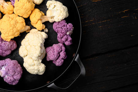 Fresh heads cleaned cauliflower set, on frying cast iron pan, on black wooden table background, top view flat layの写真素材