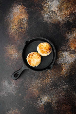 Cheese cakes Sweet pancakes set on cast iron frying pan skillet, top view flat lay, on old dark rustic table background, with copy space for textの写真素材