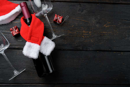 Wine bottles with Santa red hat set on black wooden table background, top view flat lay, with copy space for textの写真素材