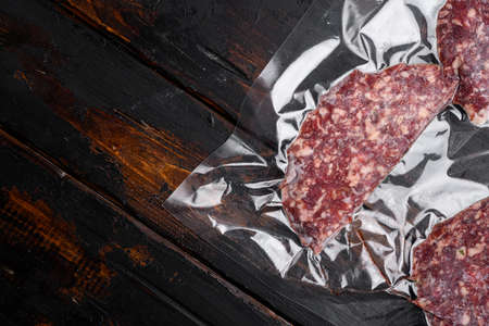 Beef veal cutlets in vacuum plastic pack set on old dark wooden table background, top view flat lay, with copy space for textの写真素材