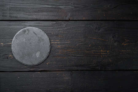 Slate stone cutting board set with copy space for text or food with copy space for text or food, top view flat lay, on black wooden table backgroundの写真素材