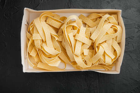Raw pappardelle set, on black dark stone table background, top view flat layの写真素材