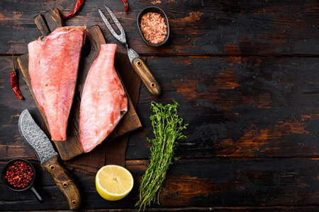 Red perch fish meat set, on wooden cutting board, on old dark wooden table background, top view flat...