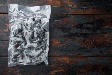 Frozen Mussels in vacuum pack, on dark wooden background, top view flat lay , with copyspace and space for textの写真素材