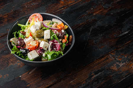 Greek salad with feta cheese and organic fresh olives, on old dark wooden table background with copy space for textの写真素材