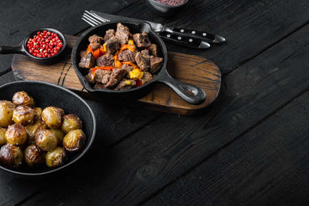 Irish stew made with beef, potatoes, carrots and herbs set, in cast iron frying pan, on black wooden background, with copy space for textの写真素材