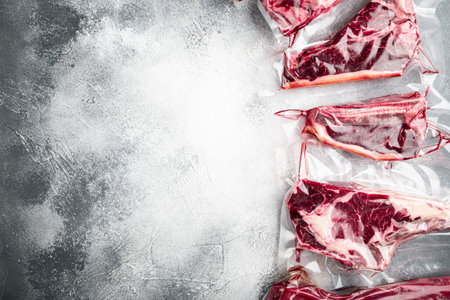 Fresh tasty raw beef steaks with bone wrapped in vacuum plastic packing at market set, tomahawk, t...