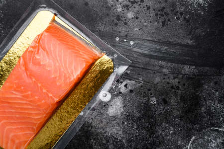 Red fish fillet in vacuum pack set, on black dark stone table background, top view flat lay, with copy space for textの写真素材