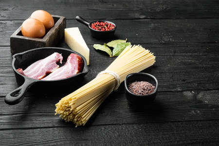 Fresh raw ingredients for traditional italian pasta Carbonara set, on black wooden background, with copy space for textの写真素材
