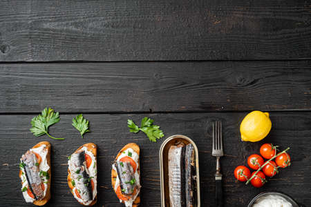 Crostini with fish and ricotta, on black wooden table background, top view flat lay, with copy space for textの写真素材