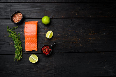 Raw Fillet of salmon set, with herbs, on black wooden table background, top view flat lay, with copy...