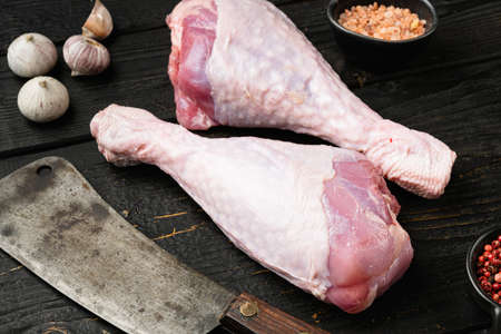 Turkey meat, raw thigh with spices set, with old butcher cleaver knife, on black wooden table backgroundの写真素材