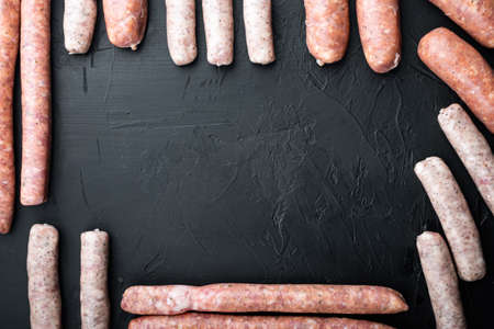 Set of pork, beef and chicken sausages, frame or border concept, flat lay with space for text, on black background.の写真素材