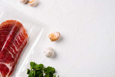 Italian dry cured ham vacuum pack set, on white stone table background, top view flat lay, with copy space for textの写真素材