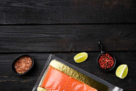 Fillet of red vacuum packed fish set, with herbs, on black wooden table background, top view flat lay, with copy space for textの写真素材