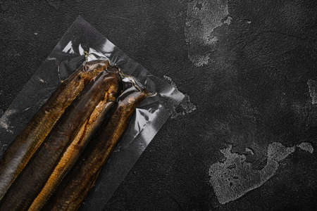 Smoked Lamprey seafood delicacy vacuum pack set, on black dark stone table background, top view flat lay, with copy space for textの写真素材