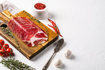 Sliced cured coppa ham set, on white stone table background, with copy space for text