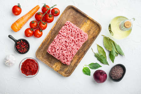 Bolognese sauce ingredients, minced meat tomato and herbs set, on wooden tray, on white stone background, top view, flat layの写真素材