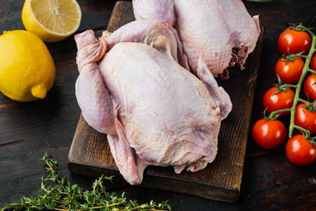 Raw coquelet chickens meat with ingredients, on old wooden tableの写真素材