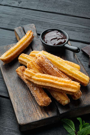Churros sprinkled with powdered sugar set, on black wooden table backgroundの写真素材