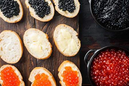 Canapes with black sturgeon, and salmon fish caviar, on old dark wooden table background, top view flat layの写真素材