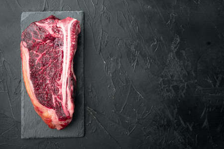 Raw beef meat marbled dry aged Club or striploin on the bone steak set, on black stone background, top view flat lay, with copy space for textの写真素材
