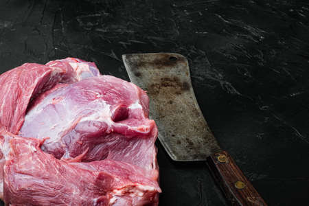 Fresh pork meat set , with old butcher cleaver knife, on black dark stone table background, with copy space for textの写真素材