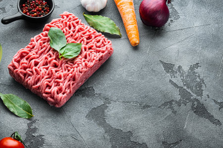 Ingredients for cooking Bolognese sauce, minced beef meat tomatoe and herbs set, on gray stone...