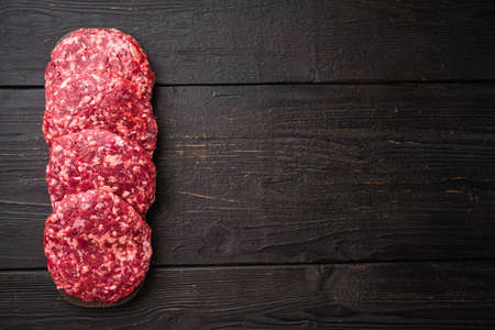 Patty of minced meat for burger set, on black wooden table background, top view flat lay, with copy space for textの写真素材
