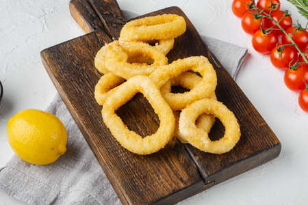 Fried squid rings breaded set, on serving board, on white stone table backgroundの写真素材