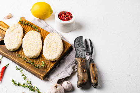 Raw meat patty cutlets with breadcrumbs set, on white stone table background, with copy space for...