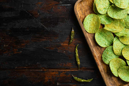 Green potato chips, on old dark wooden table background, top view flat lay, with copy space for textの写真素材