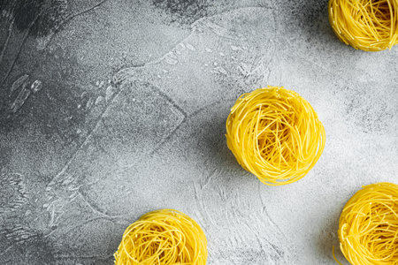 Unooked Italian Tagliolini paglia pasta set, on gray stone background, top view flat lay, with copy...