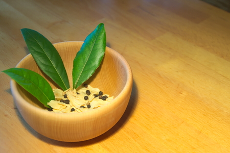 Bay leaves in wooden bowl with dry garlic and pepperの写真素材