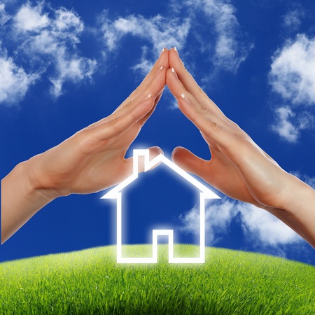 Human hand against blue sky background and houseの写真素材