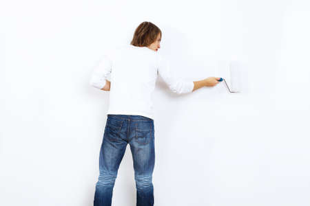 Young man with paint brush and blank white wallの写真素材