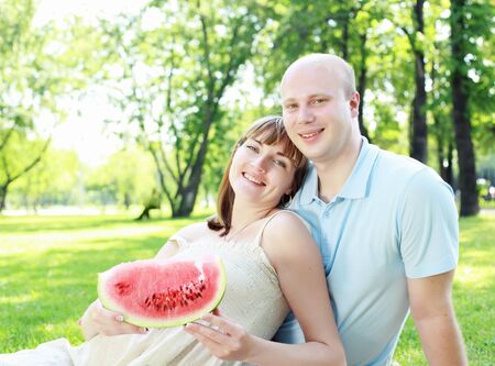 Young couple with a pregnant wife on picnic in the parkの写真素材