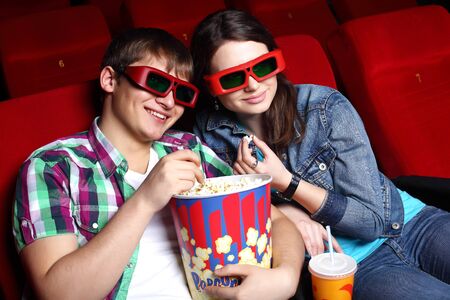 Young couple sitting in cinema and watching movieの写真素材