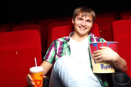 Young man sitting in cinema and watching movieの写真素材